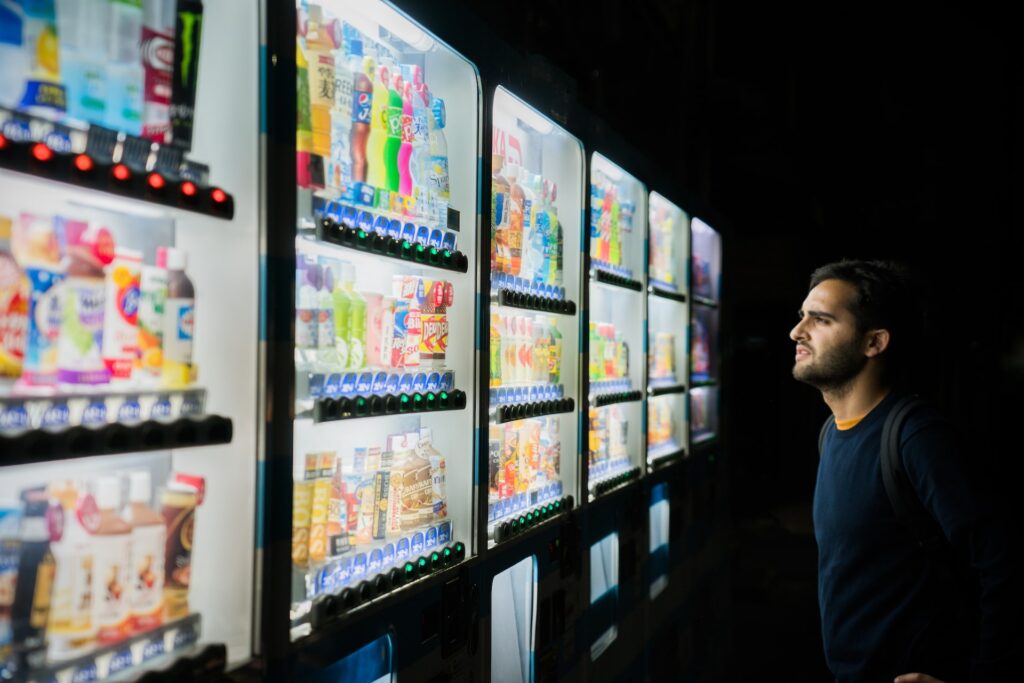 vending machine with many juices and a boy starring at the vending machine